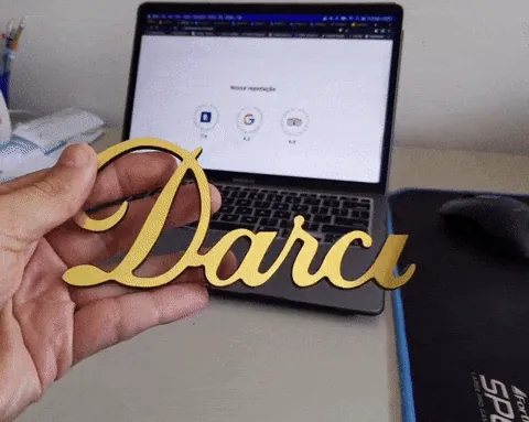 Gold cemetery lettering prototype held up in front of a laptop